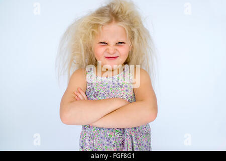 Young girl with messy blonde hair frowning with folded arms and a cheeky grin