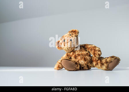 Brown teddy bear sitting on the floor leaning to one side Stock Photo