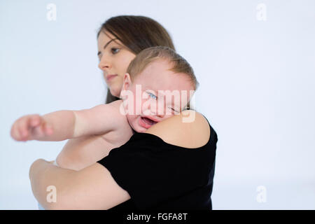 Mother holding baby son in arms crying Stock Photo