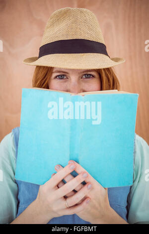 blue eyed hipster woman looking over the top of a book Stock Photo