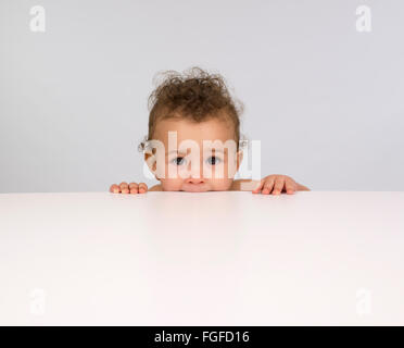 Cute baby boy peeping over a table top Stock Photo