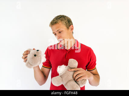 Man holding the head and body of a cute toy teddy bear looking sad Stock Photo