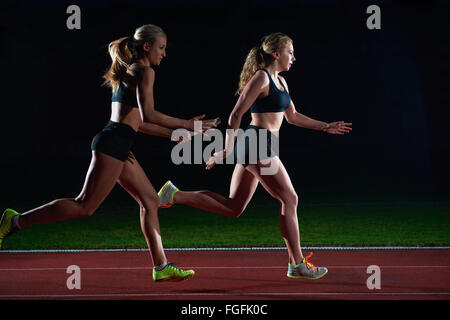 athletic runners passing baton in relay race Stock Photo