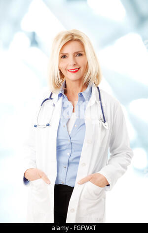 Portrait of female doctor with stethoscope standing at hospital while her hands in pockets and looking at camera. Stock Photo