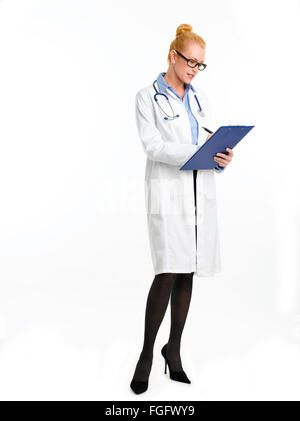 Full length portrait of female doctor standing agains white background. Healtcare worker holding clipboard and writing patient l Stock Photo