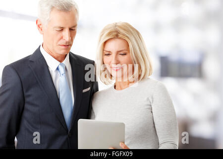 Portrait of successful sales team working with digital tablet while standing at office. Teamwork. Stock Photo