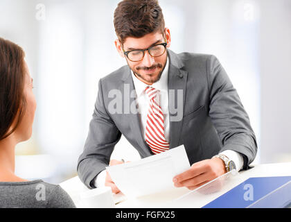 Portrait of young businessman interviewing young business woman, while sitting at desk at office. Business people. Stock Photo