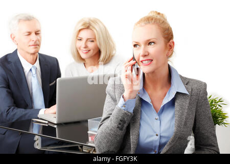 Portrait of executive business woman using her mobile while business team working with laptop at background. Isolated on white b Stock Photo