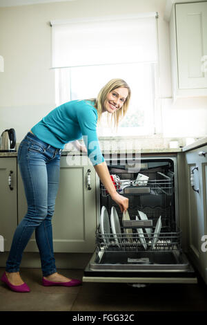 Pretty blonde woman emptying the dishwasher Stock Photo