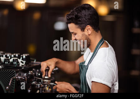 Smiling barista preparing coffee with a machine Stock Photo