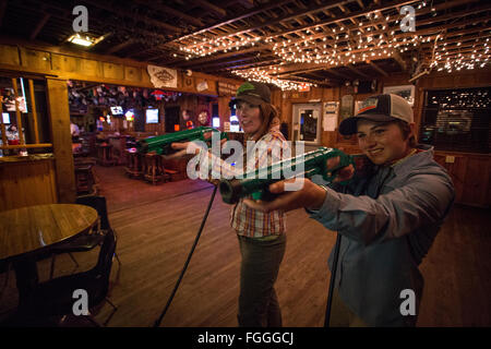 Two women laugh and play a video game in a Montana bar. Stock Photo