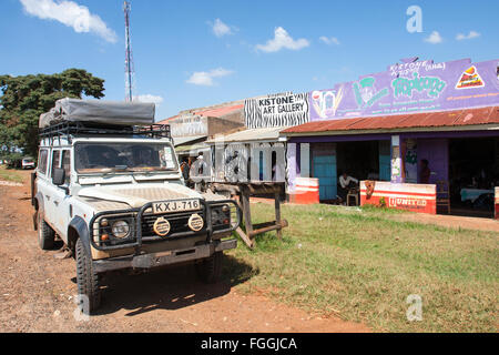 Old Land Rover Defender 110  parked outside rustic tourist art or gift shops Kistone  Kenya Stock Photo