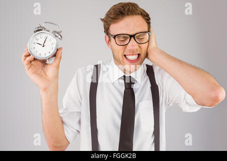 Geeky businessman holding alarm clock Stock Photo