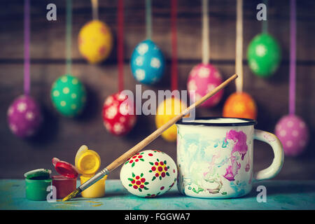 Painting Easter eggs and hanging colorful eggs on rustic wooden background Stock Photo