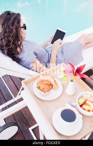 Young woman relaxing on a sun lounger near poolside Stock Photo