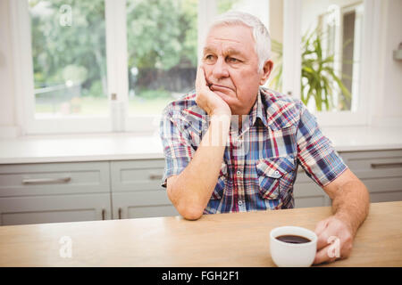 Thoughtful senior man sitting at table Stock Photo