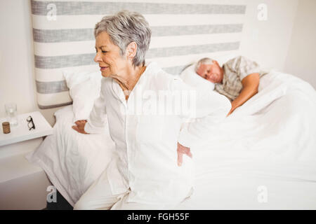 Senior woman suffering from backache sitting on bed Stock Photo