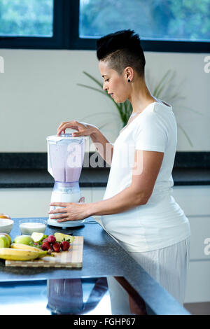 Pregnant woman preparing fruit juice in blender Stock Photo