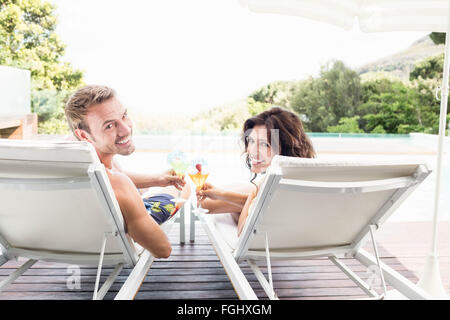 Young couple sitting on sun loungers Stock Photo