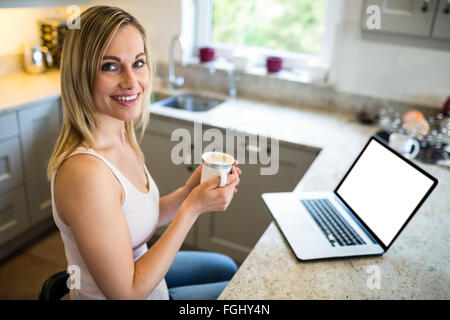 Pretty blonde woman having coffee and using laptop Stock Photo