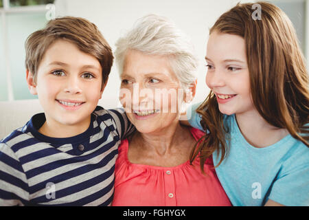 Grandmother and grandchildren sitting together on sofa Stock Photo