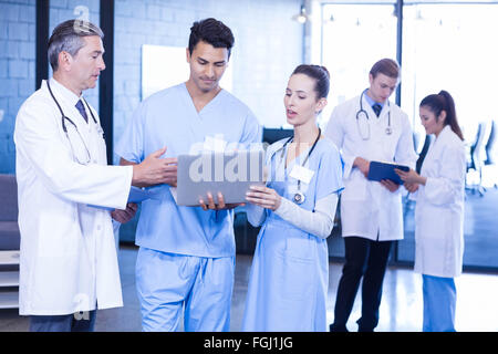 Medical team using laptop, digital tablet and examining medical report Stock Photo