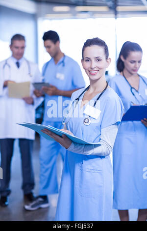Female doctor holding medical report and smiling at camera Stock Photo