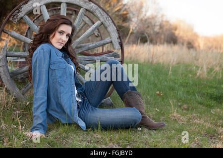 Beautiful brunette woman wearing jeans and boots in a country setting Stock Photo