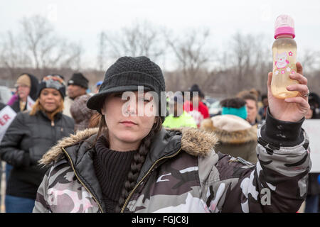 Flint, Michigan USA - 19th February 2016 - Residents marched to the Flint water treatment plant to demand the rebuilding of the city's water infrastructure. A woman carries a bottle of Flint tap water. Credit:  Jim West/Alamy Live News Stock Photo