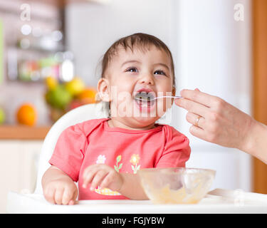 smiling baby eating food on kitchen Stock Photo