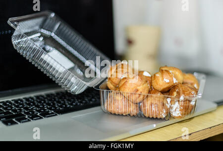 delicious eclairs with coffee on a laptop computer warm tone Stock Photo