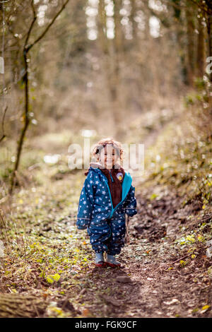 Mixed race three year old boy enjoying playing in woodland. Stock Photo