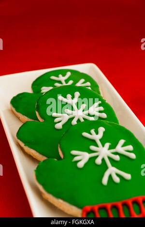 Holiday mitten cookies on a white platter and red background Stock Photo