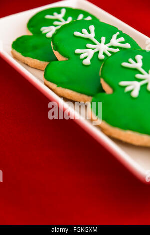 Holiday mitten cookies on a white platter and red background Stock Photo