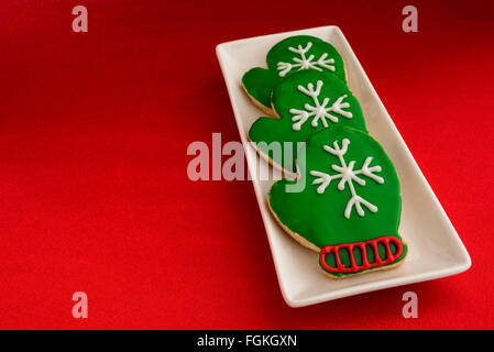 Holiday mitten cookies on a white platter and red background Stock Photo