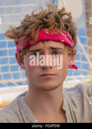 a good looking young man with head bandana headband and messy tousled hair looking at camera with a quizzical look gaze Stock Photo