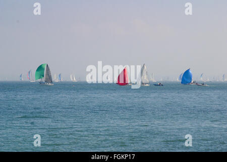 a group of racing yachts on a sunny day with primary colour color spinnakers Round the Island Isle of Wight sailing regatta UK Stock Photo