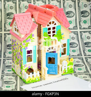 Cute little doll house on money with Home Sweet Home sign Stock Photo