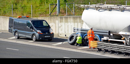 Breakdown van & fitter with driver attend broken down tanker lorry on hard shoulder M25 motorway having a wheel tyre problem fixed Essex England UK Stock Photo