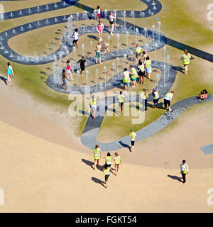 Aerial view kids play outdoors in water fountain jets school trip hot summer day Queen Elizabeth Olympic Park London Newham Stratford East London UK Stock Photo