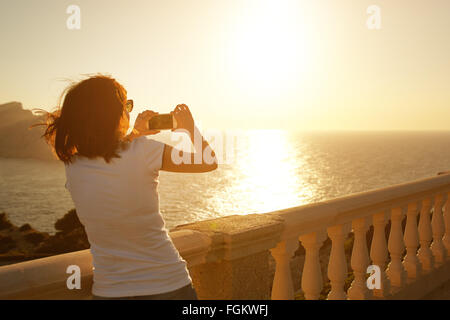 Girl photographing sunset with her phone Stock Photo