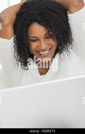 Happy, smiling, beautiful smiling African American woman at home laughing using her laptop computer. Stock Photo