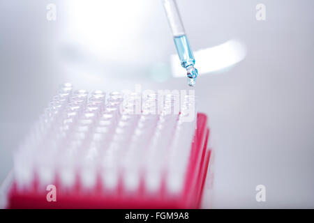 Blue liquid dripping from pipette into test tube Stock Photo