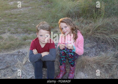 Boy and Girl twins sitting on a rock in the country looking at camera Stock Photo