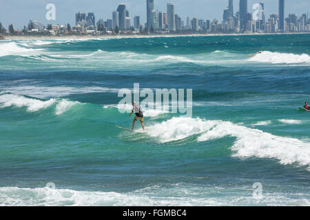 man surfing in the ocean at Burleigh Heads with Surfers Paradise  in the distance,Gold coast,Queensland,Australia Stock Photo