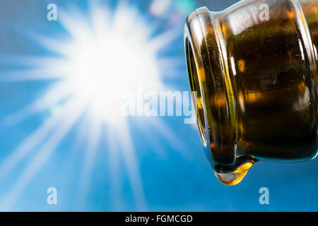 Last drop of an empty beer bottle with the sun in the background Stock Photo