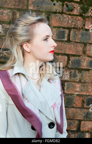 Profile of a woman from the forties era standing beside a brick wall Stock Photo