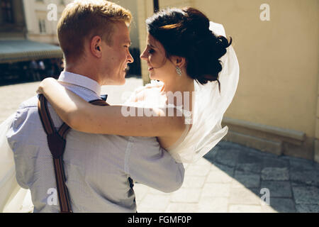 groom carries bride in his arms Stock Photo