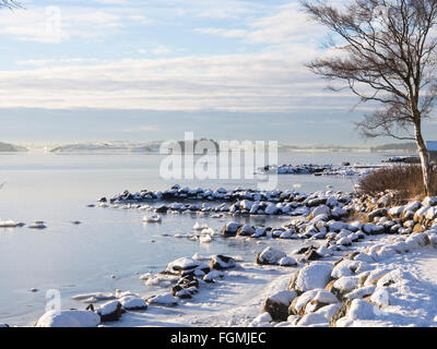 Idyllic sunny winter day on the shore of Hafrsfjord in Stavanger Norway, ice and snow  cover , calm blue white landscape Stock Photo