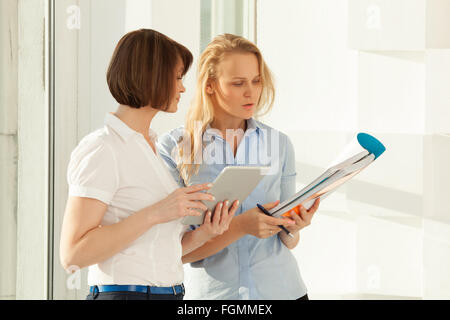 Two colleagues talking while looking at notebook Stock Photo